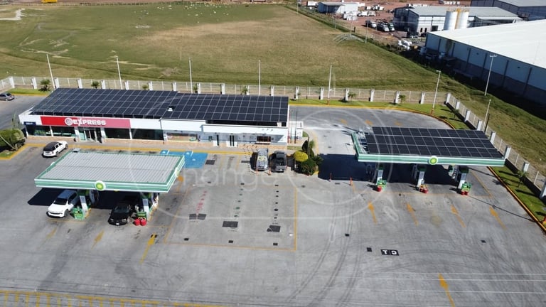 Aerial view of a commercial building with solar panels on the roof and parking lot below.
