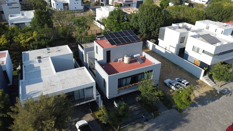 Aerial view of modern residential neighborhood with contemporary houses featuring solar panels and flat roofs.