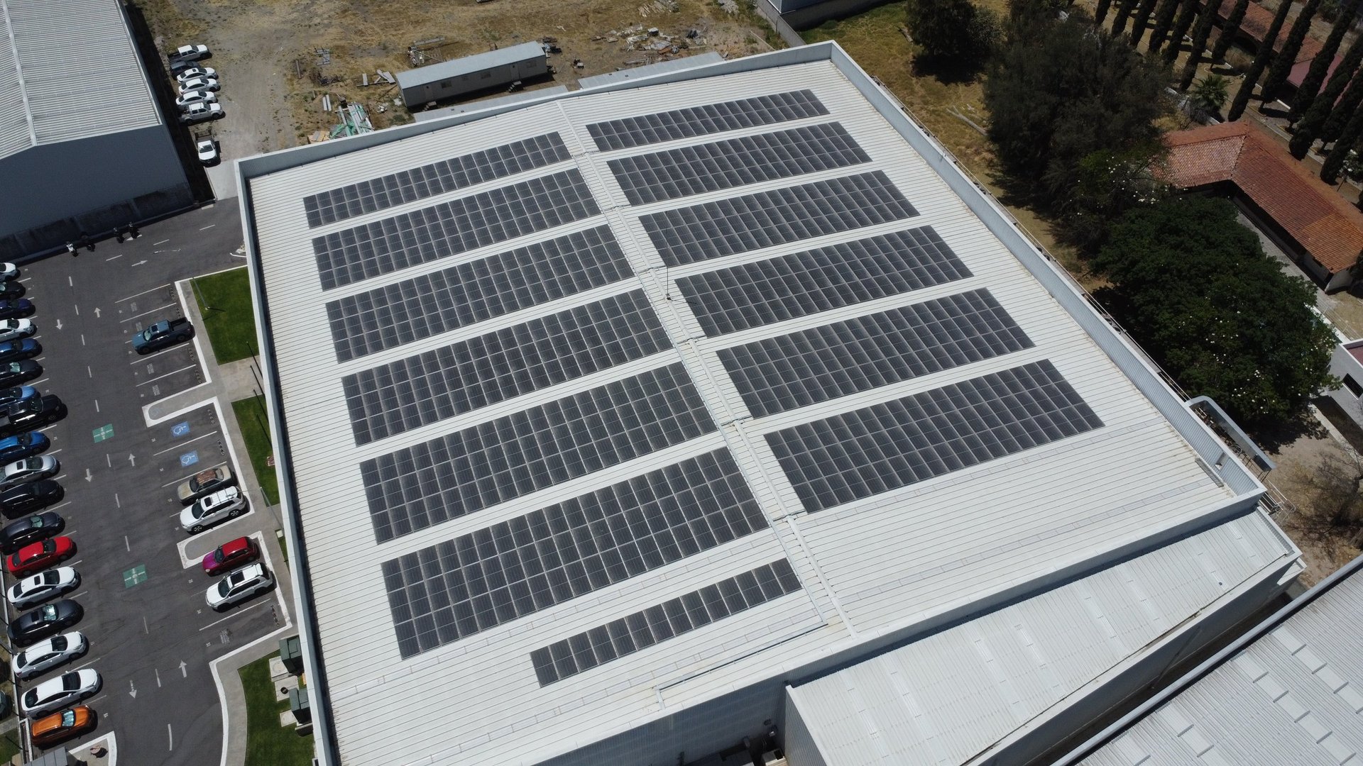 Aerial view of solar panels installed on a commercial building roof above a parking lot