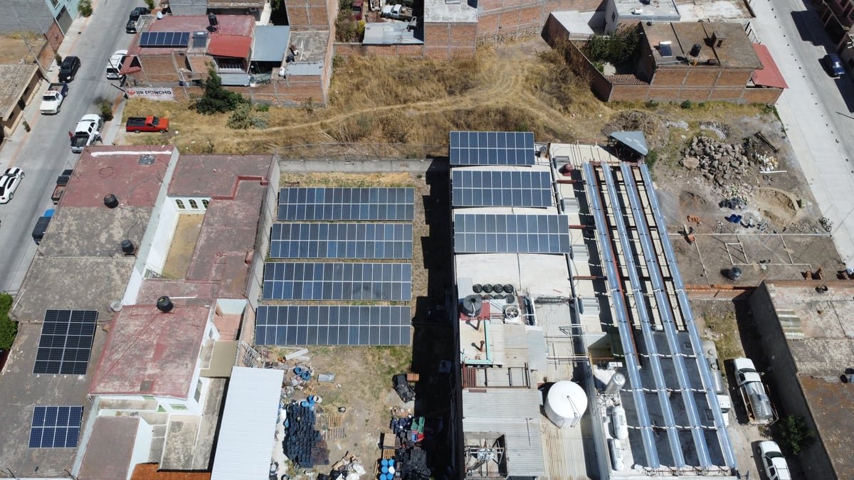 Aerial view of industrial buildings with multiple solar panel arrays installed on rooftops